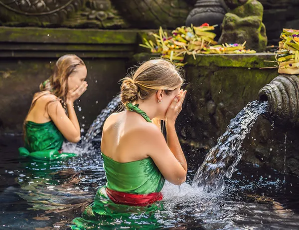foto från bali, två kvinnor i gröna baddräkter i en fontän